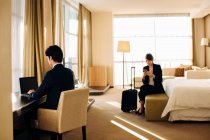 Бізнесмен і бізнес-леді, що працюють в спальні готелю — стокове фото