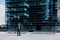 Empresário usando smartphone na frente do prédio de escritórios — Fotografia de Stock