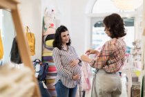 Pregnant woman shopping for baby clothes — Stock Photo
