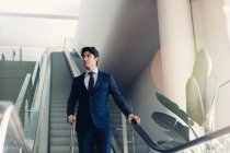 Geschäftsmann mit Rollgepäck auf Hotelrolltreppe — Stockfoto