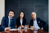 Businessmen and woman at boardroom table listening to presentation — Stock Photo