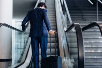 Бізнесмен з колісним багажем на ескалаторі готелю — стокове фото