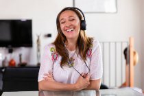 Smiling woman wearing headphones talking online during Coronavirus lockdown. — Stock Photo