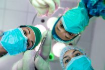 Tiefansicht von drei Chirurginnen mit Operationsmasken, die in die Kamera schauen. — Stockfoto
