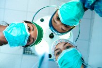 Tiefansicht von drei Chirurginnen mit Operationsmasken, die in die Kamera schauen. — Stockfoto