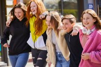 Group of teenage girls and boy walking side by side outdoors. — Stock Photo