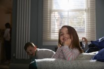 Zwei Kinder sitzen im Schlafanzug auf einem Sofa und lächeln in die Kamera. — Stockfoto