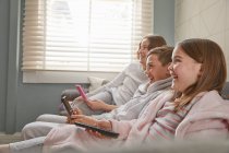 Group of children sitting on a sofa in their pajamas, watching television. — Stock Photo