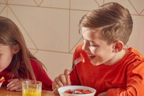 Boy and girl sitting at kitchen table, eating breakfast. — Stock Photo