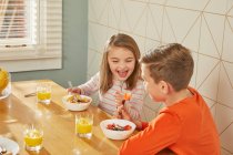 Мальчик и девочка сидят за кухонным столом, завтракают. — стоковое фото