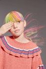 Porträt eines Mädchens mit langen, bunten Haaren und gefärbten Fransen, das ein rosafarbenes Rüschenoberteil trägt und mit hängenden Augen wegschaut — Stockfoto