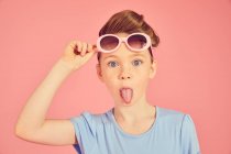 Ritratto di ragazza bruna su sfondo rosa, che sporge la lingua davanti alla macchina fotografica — Foto stock