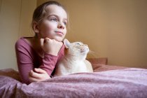 Portrait of girl and white and ginger cat lying on bed. — Stock Photo