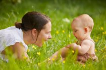 Mãe e bebê filha brincando em um prado. — Fotografia de Stock