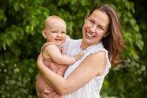 Portrait of mother and baby daughter smiling at camera. — Stock Photo