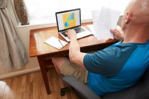 Mann sitzt mit Laptop an kleinem Schreibtisch und arbeitet während der Coronavirus-Krise zu Hause. — Stockfoto