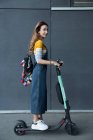 Young woman with long brown hair standing on electric scooter. — Stock Photo