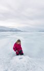 Fille regardant trou de pêche sur glace sur le lac gelé à Vasterbottens Lan, Suède. — Photo de stock
