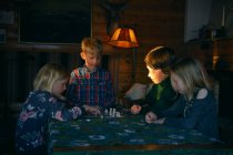 Grupo de niños sentados en una mesa en una cabaña de troncos, jugando ajedrez, Vasterbottens Lan, Suecia. - foto de stock