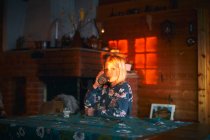 Ragazza seduta a un tavolo in una capanna di legno, bere un bicchiere d'acqua, Vasterbottens Lan, Svezia. — Foto stock
