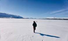 Rückansicht von zwei Jungen, die über den zugefrorenen See in Vasterbottens Lan, Schweden laufen. — Stockfoto