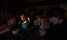 Grupo de crianças sentadas a uma mesa em uma cabine de madeira, comendo, Vasterbottens Lan, Suécia. — Fotografia de Stock