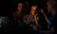 Ragazzo e due ragazze seduti a un tavolo in una capanna di legno, mangiare, Vasterbottens Lan, Svezia. — Foto stock