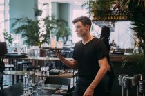 Young man wearing black clothes working in bar, carrying drinks on a tray. — Stock Photo