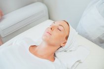Femme couchée sur le lit de traitement dans un salon de beauté. — Photo de stock