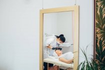 Immagine a specchio di donna che si fa fare le sopracciglia in un salone di bellezza. — Foto stock