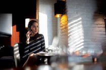 Бізнес-леді сидить за столом, використовуючи мобільний телефон . — стокове фото