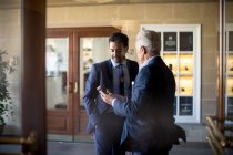 Двое бизнесменов, стоящих в холле отеля, разговаривают. — стоковое фото
