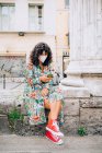 Junge Frau trägt Gesichtsmaske während Coronavirus, sitzt im Freien und checkt Handy. — Stockfoto