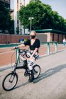 Mujer joven con máscara facial durante el virus Corona, ciclismo en bicicleta plegable. - foto de stock