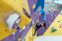 Side view of woman ascending rock climbing wall. — Stock Photo