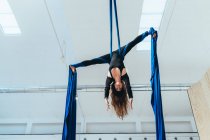 Aerista acrobata femminile praticante, sospesa a una lunghezza di seta blu — Foto stock