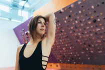 Woman in black outfit standing in front of indoor rock climbing wall. — Stock Photo