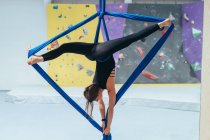 Acrobate acrobate féminin pratiquant, suspendu à une longueur de soie bleue — Photo de stock