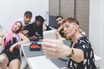 Friends taking selfie on mobile phone while sitting in kitchen — Stock Photo