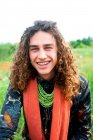 Sorridente homem, retrato de jovem com longos cabelos castanhos encaracolados no prado de papoilas — Fotografia de Stock