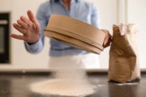 Woman standing in a kitchen, making fresh homemade pasta, sifting flour. — Stock Photo