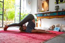 Frau praktiziert Yoga drinnen auf rotem Teppich. — Stockfoto