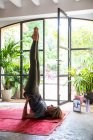 Mujer practicando yoga en interiores sobre alfombra roja. - foto de stock