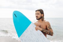 Surfista con tabla de surf junto al mar - foto de stock