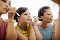 Friends putting on makeup at mirror, close-up view — Stock Photo