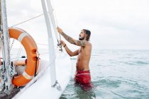 Mann bereitet Segelboot im Meer vor — Stockfoto