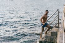Man going up steps from sea — Stock Photo