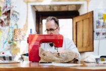 Чоловік використовує швейну машину в творчій студії — стокове фото