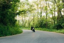Jovem motociclista do sexo masculino em motocicleta vintage na estrada rural curva, Florença, Toscana, Itália — Fotografia de Stock