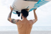 Surfer with surfboard by seaside — Stock Photo